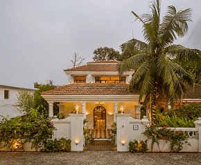 Illuminated heritage villa entrance framed by palms